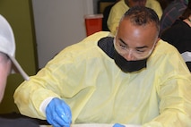 U.S. Air National Guard Tech. Sgt. Jacob Jackson performs sutures on the limb of a postmortem human model that is out of view