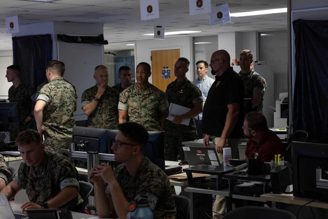 U.S. Marine Corps Lt. Gen. Calvert L. Worth, the commanding general of II Marine Expeditionary Force, center, receives a brief during exercise Scarlet Dragon 25-3 at Marine Corps Base Camp Lejeune, North Carolina, Aug. 14, 2025. Beginning in 2020, the Scarlet Dragon series of exercises were founded by XVIII Airborne Corps to serve as a venue for all services, to use data, artificial intelligence, and Combined Joint All-Domain Command and Control to enable decision dominance in training their mission essential tasks. (U.S. Marine Corps photo by Sgt. Andrew King)