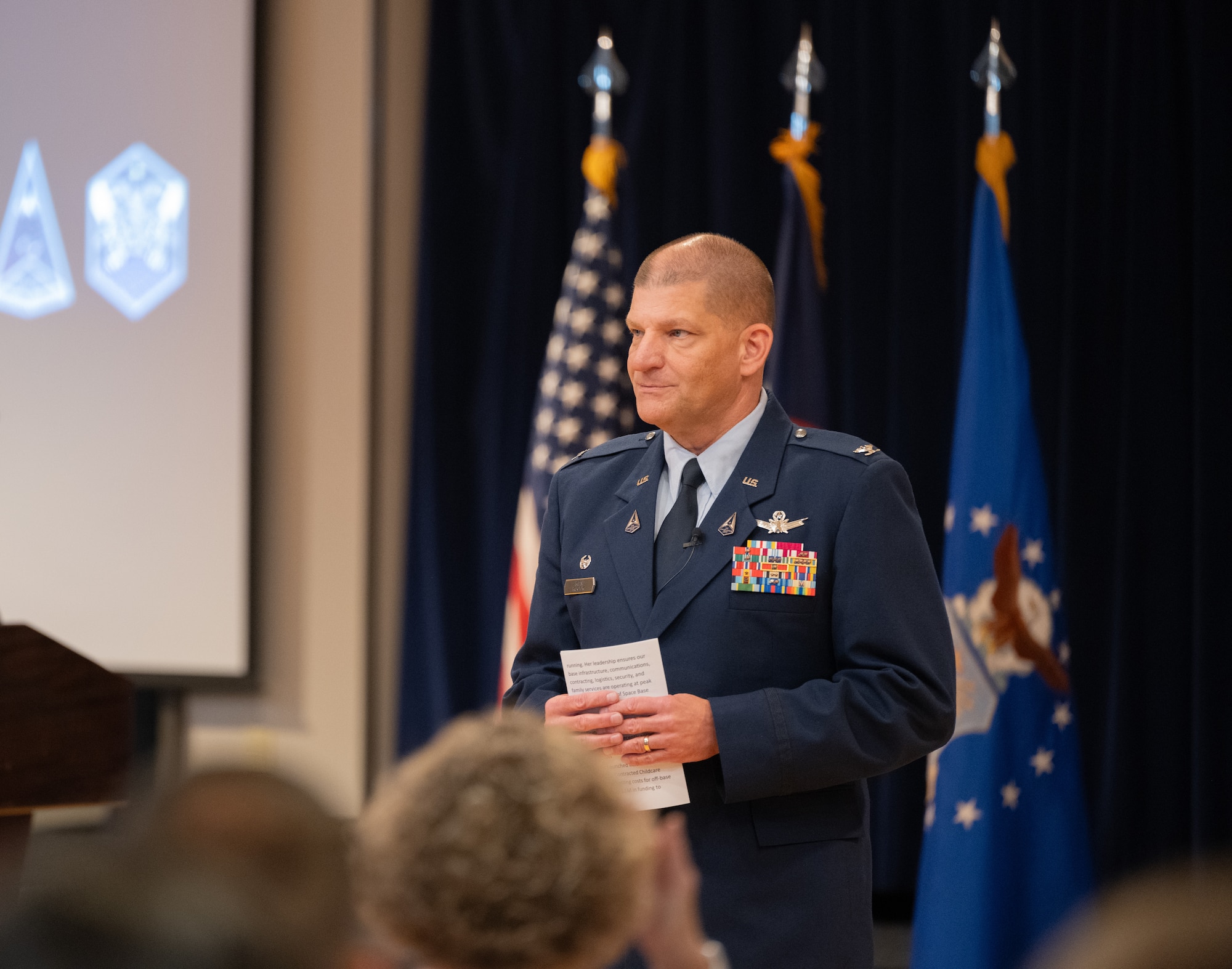 Col. Klock stands in front of the audience during the State of the Bases