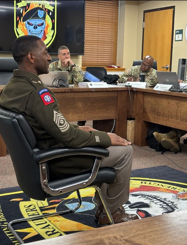 Soldier in ASGUs in an office setting sits before a board panel.