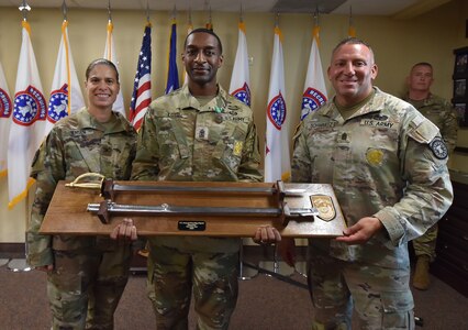 "First Sergeant of the Year" poses with his award in an office.