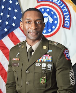 Command photo of Soldier in ASGUs in front of the U.S. flag and the USAREC flag.