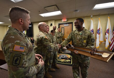 Soldier is congratulated on his accomplishments in an office setting.