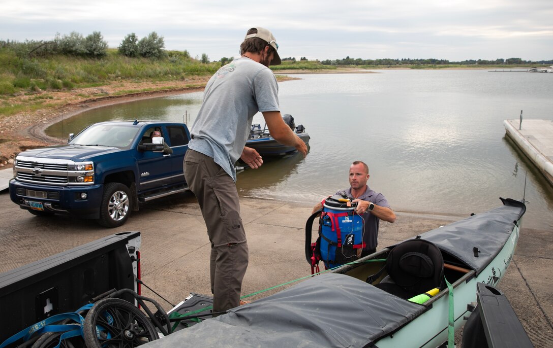 Scott Sterling, a natural resources specialists and ranger with the U.S. Army Corps of Engineers, Omaha District’s Garisson Project in North Dakota, hands a food barrel to Kyle Parker at the Lake Sakakawea boar ramp, July 17, 2025.