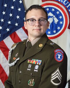 Army Soldier in dress uniform poses in front of American and USAREC flags