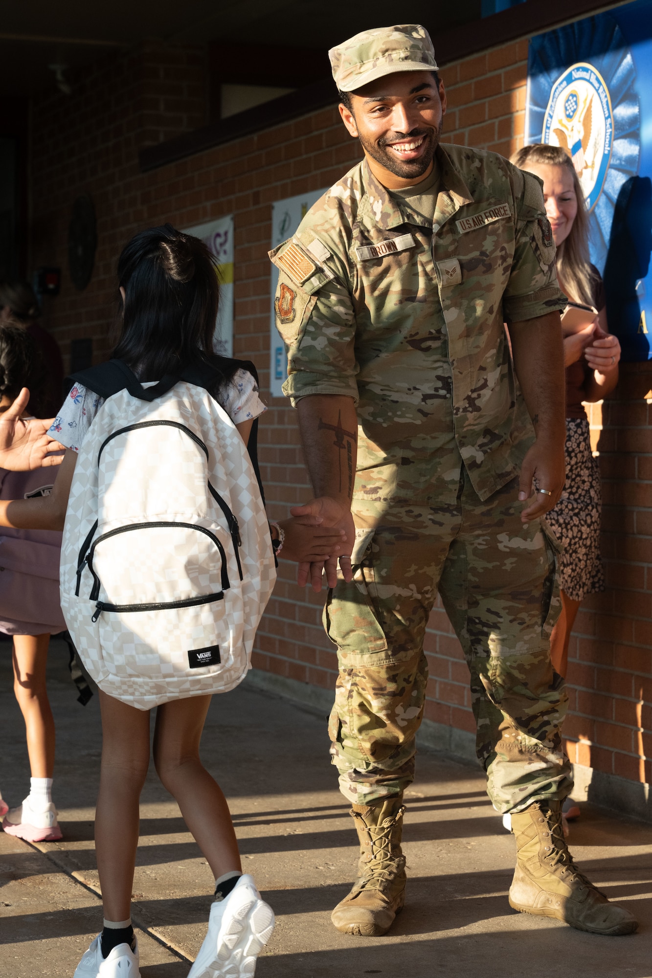 Senior Airman Amelio Brown, 22nd Air Refueling Wing public affairs apprentice, high fives a student at Wineteer Elementary, Wichita, Kansas, Aug. 13, 2025. Airmen were able to volunteer to greet students at seven different schools in the local area during the first two weeks of school. (U.S. Air Force photo by Senior Airman Felicia Przydzial)