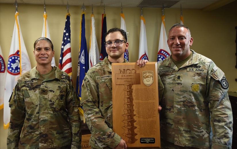 Army Soldiers smile and show off an award plaque