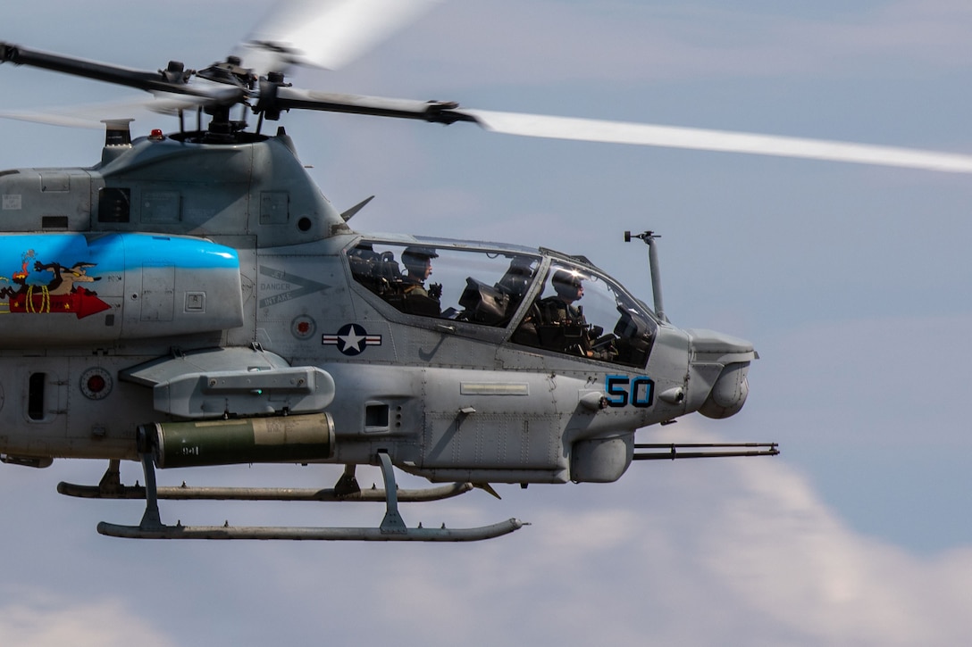 A close-up of Marines flying in a helicopter in a cloudy, blue sky.