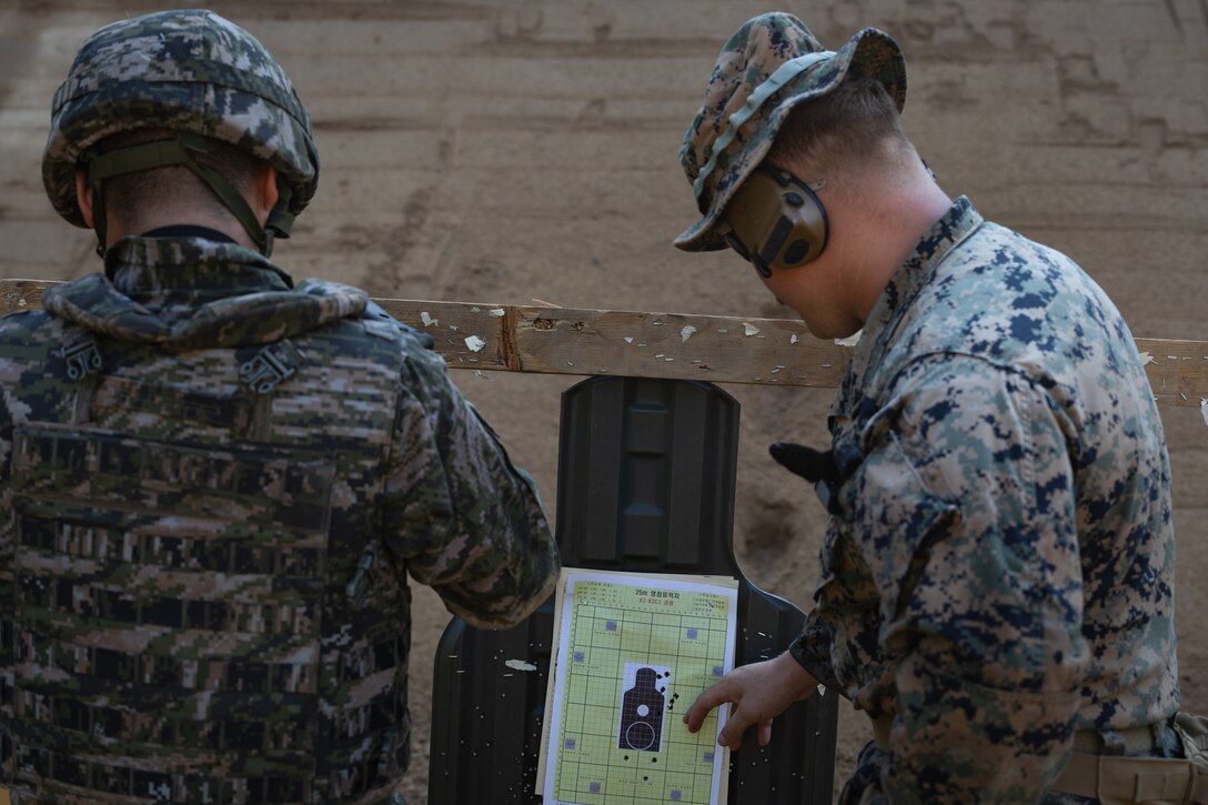 A U.S. Marine with 2nd Battalion, 23rd Marines, forward deployed with 4th Marine Regiment, 3d Marine Division as part of the Unit Deployment Program, and a Republic of Korean Marine check their shot groupings at a battle sight zero range during the Korean Marine Exchange Program 25.2 in Pocheon, South Korea, July 26, 2025. KMEP is conducted regularly between the ROK and U.S. Marine Corps to increase their combined capabilities through realistic training geared towards deterrence and maintaining peace in the Indo-Pacific. (U.S. Marine Corps photo by Lance Cpl. Van Hoang)