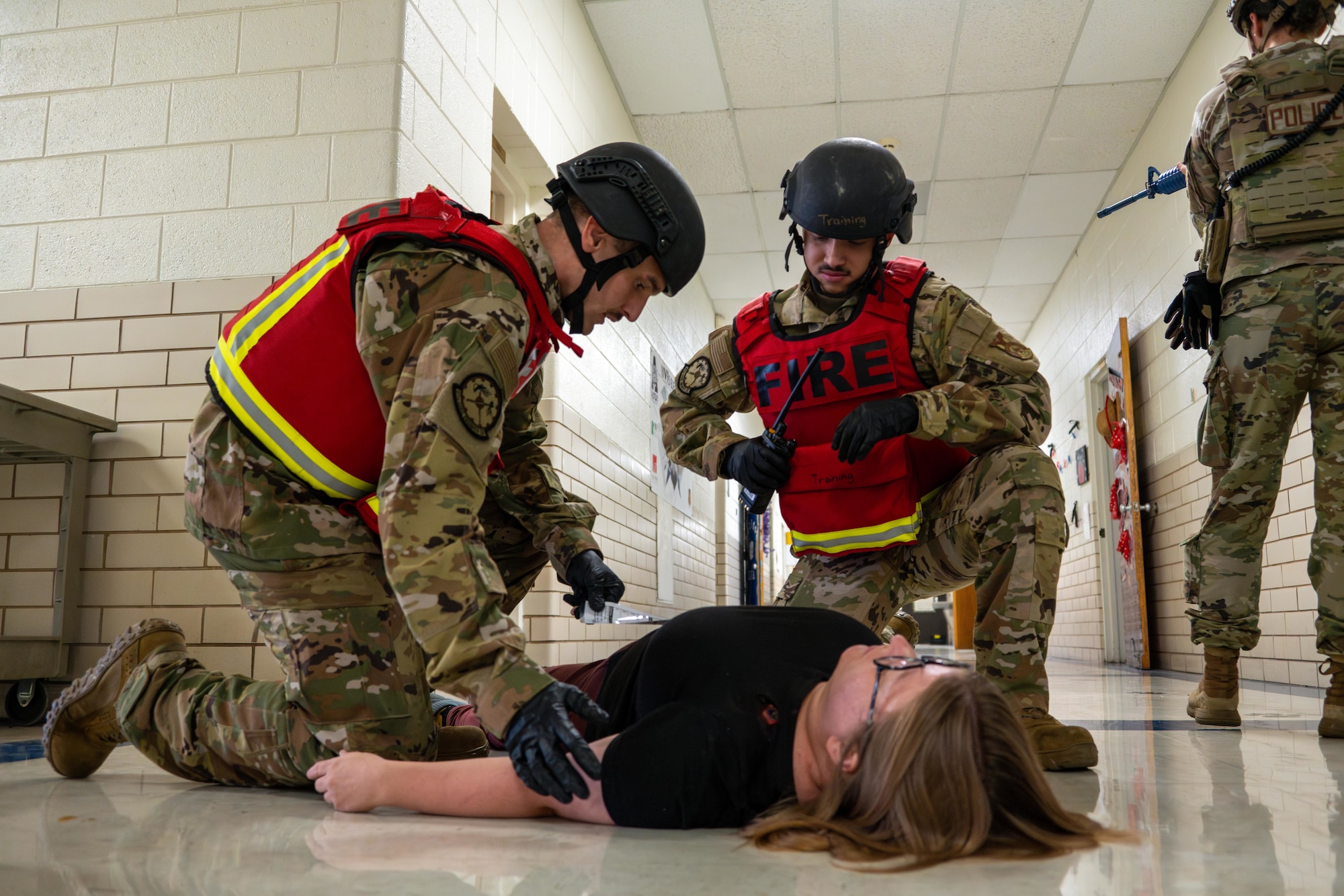 U.S. Air Force Airmen 1st Class Mathew Gates and Andrew Ryan, 97th Civil Engineer Squadron firefighters, tend to a simulated victim during an active shooter exercise at L. Mendel Rivers Elementary School at Altus Air Force Base, Oklahoma, Aug. 12, 2025. With the simulated threat neutralized, firefighters stepped in to deliver immediate aid and safely extract the victims from the building. (U.S. Air Force photo by Airman 1st Class Lauren Torres)