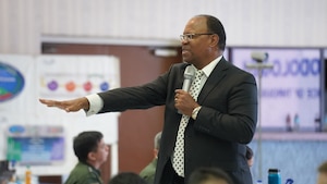 Ron Brown presenting in front of military personnel at the conference.