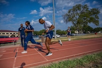 Airman is encouraged by trainer to finish his run on the track. Other trainers standing by and observing him finish the race.