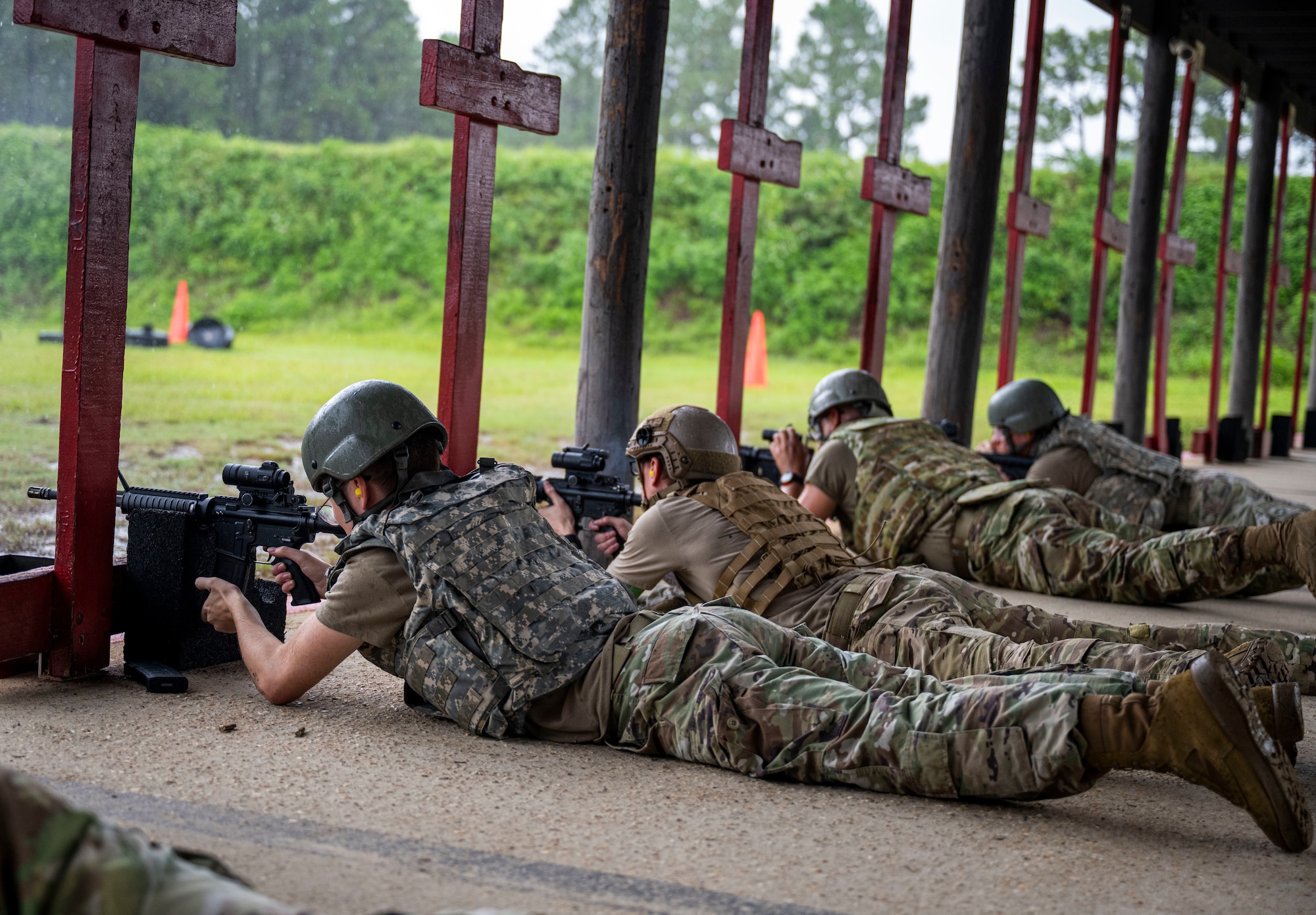 A row of Airmen are pictured firing M4 Carbines.