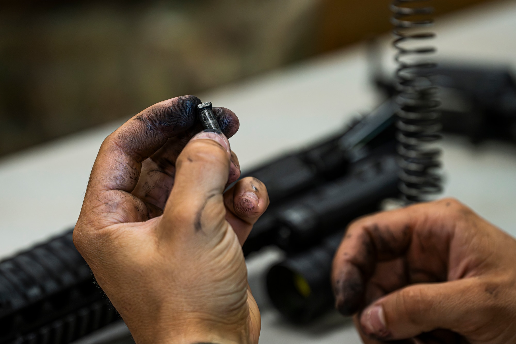 An Airmen holds a cam pin in their hand.