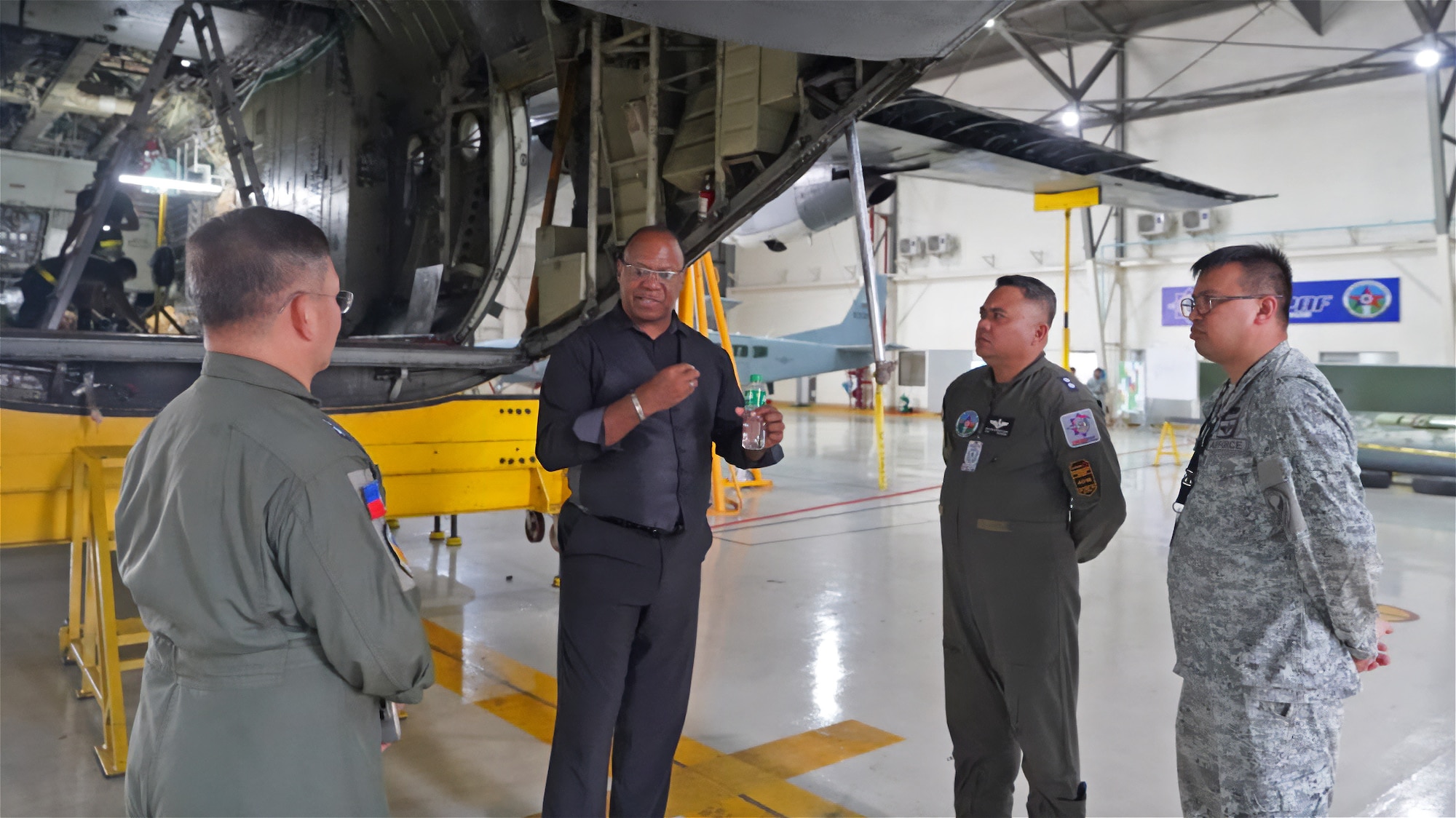 Ron Brown and Philippine military personnel stand talking next to an aircraft undergoing maintenance.