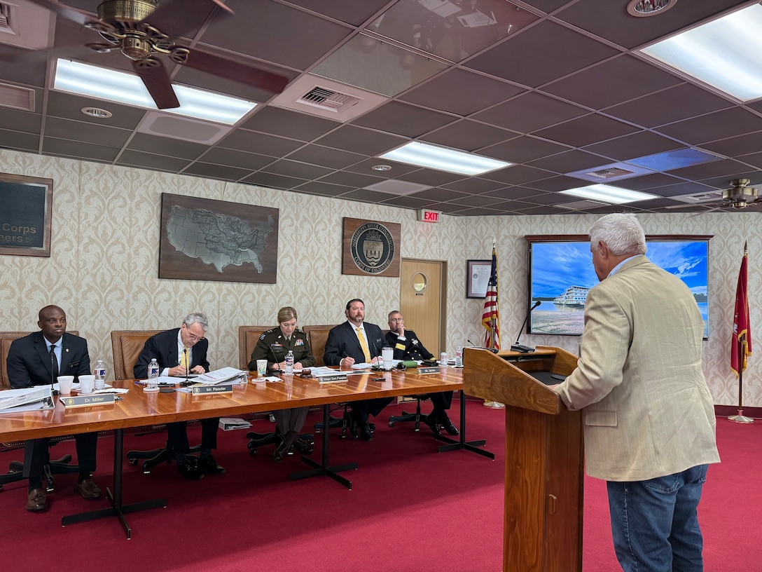 A man standing behind podium addressing a panel.