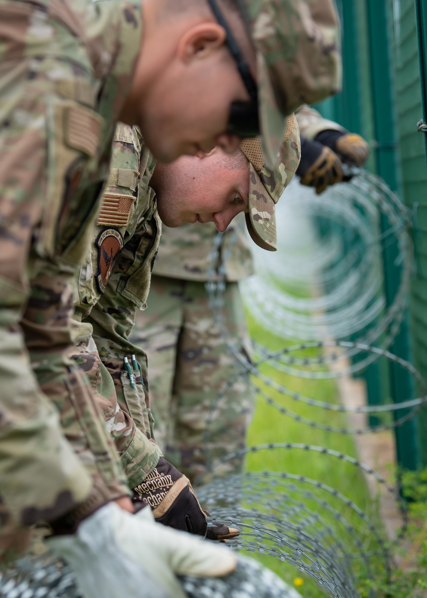 Senior Airman Darren Smallwood, a pavement and construction equipment specialist in the Kentucky Air National Guard’s 123rd Civil Engineer Squadron, unravels concertina wire at Lajes Field, Azores, June 18, 2025. The squadron collectively installed around 5,000 feet of c-wire along the base's perimeter fence during a two-week field training deployment here. (U.S. Air National Guard photo by Airman 1st Class Angelee Barnett)