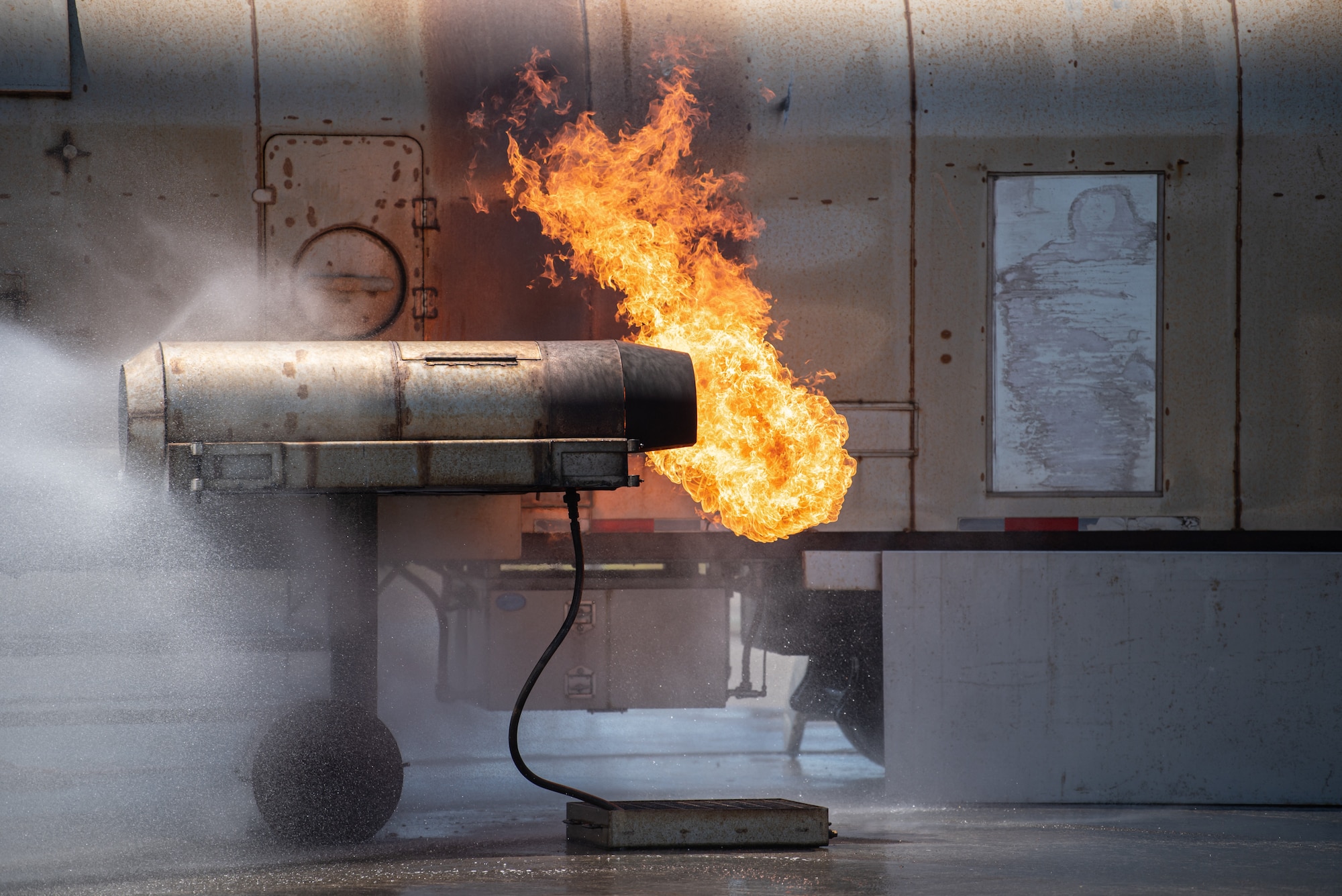 Fire spits from the mock engine of a simulated aircraft burn during an exercise at Lajes Field, Azores, June 23, 2025. The aircraft contained multiple controlled burn areas designed to train fire fighters for crisis scenarios. (U.S. Air National Guard photo by Airman 1st Class Angelee Barnett)