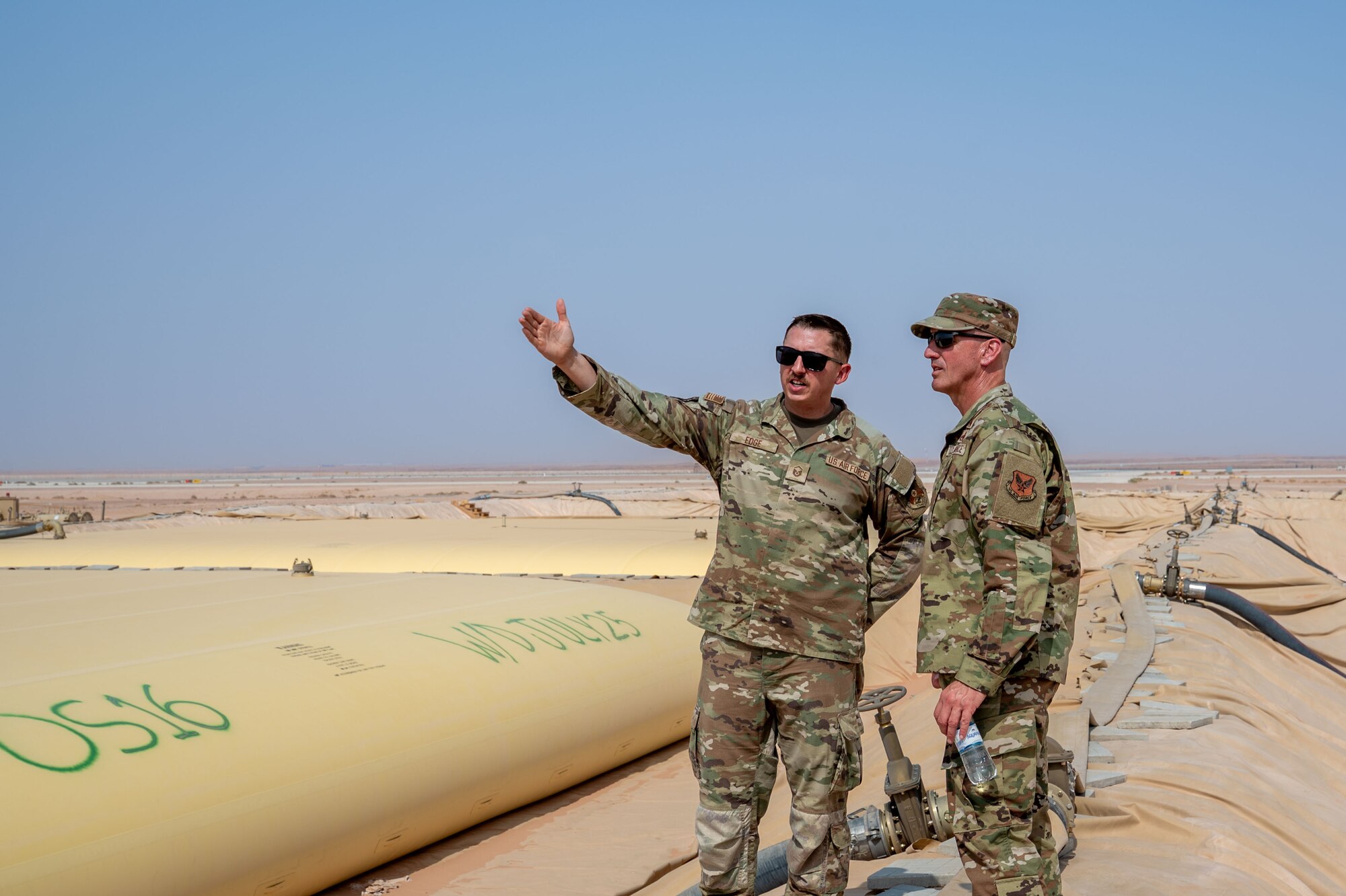 Two men observe fuel supply field.