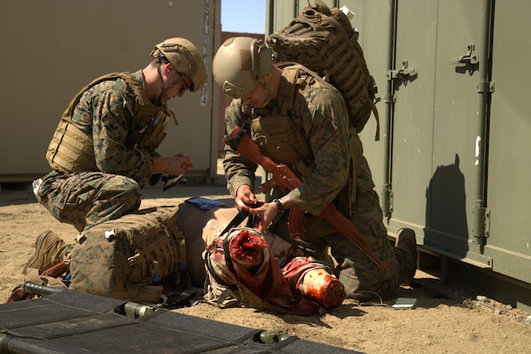 Hospitalman Sean Malone (left) and Hospitalman Ethan Nibbelink (right) apply a tourniquet and assess a simulated casualty during a combat medical training scenario, practicing lifesaving interventions under field conditions during an Expeditionary Resuscitative Surgical System (ERSS) training conducted at Naval Expeditionary Medicine Warfighter Development Center (NEMWDC), June 9-17, 2025. (U.S. Navy photo by Petty Officer 2nd Class Moira Esquivel)