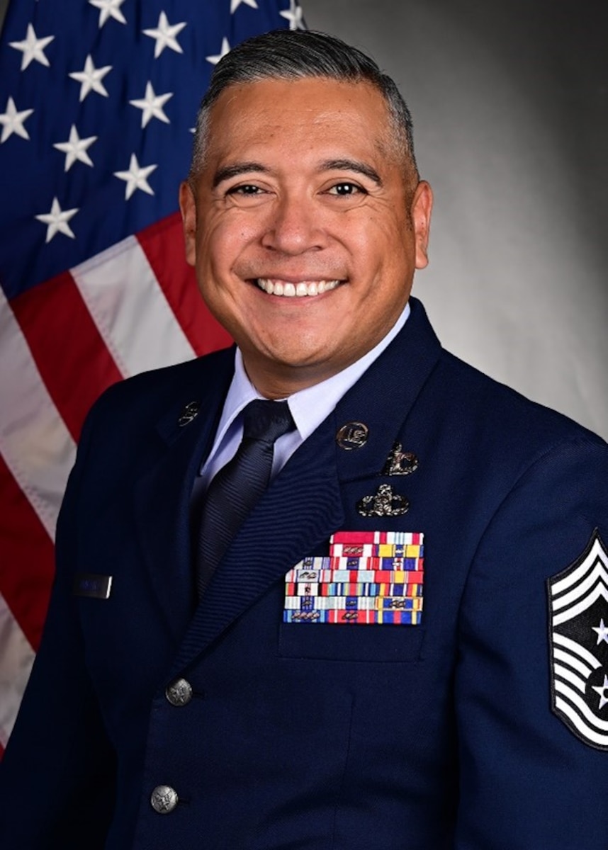 Man in military uniform posing for official photo with U.S. flag in background