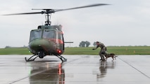 A U.S. Air Force military working dog handler and his dog run to board a helicopter in the rain.