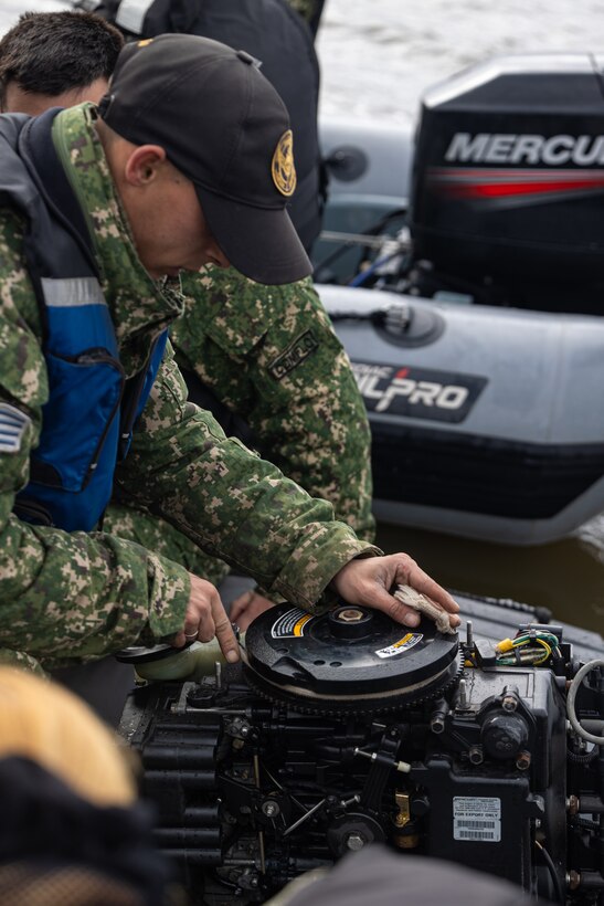 An Infante de Marina de Uruguay fixes a rigid inflatable boat engine during a subject matter expert exchange in Uruguay, August 14, 2025. This subject matter expert exchange enhances the training and readiness standards for the United States and Uruguay as well as facilitating the exchange of formalized readiness standards between both countries. (U.S. Marine Corps photo by Sgt. Eduardo Delatorre)
