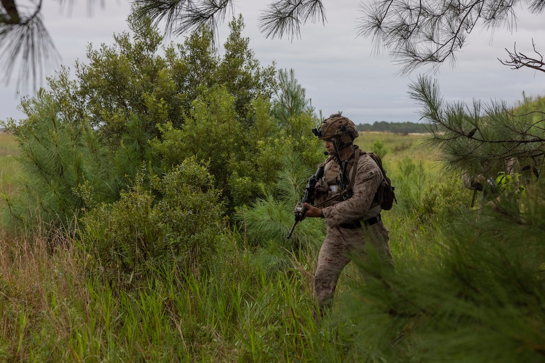 U.S. Marine Corps Capt. Nathaniel Fuiten, a field artillery officer with 2nd Air Naval Gunfire Liaison Company, II Marine Expeditionary Force Information Group, traverses the terrain at a training site during exercise Burmese Chase 25 at Marine Corps Base Camp Lejeune, North Carolina, Aug. 12, 2025. Burmese Chase is an annual U.S. led, multi-lateral training exercise comprised of integrating ground and air fires, infantry tactics and naval gunfire alongside NATO allies to enhance combat readiness and interoperability. (U.S. Marine Corps photo by LCpl. Payton Walley)
