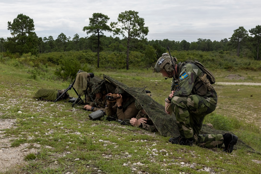 A Swedish armed forces member, right, and Dutch Marines with 25 RSTA Squadron, utilize an Android Tactical Assault Kit to observe a training site during exercise Burmese Chase 25 at Marine Corps Base Camp Lejeune, North Carolina, Aug. 12, 2025. Burmese Chase is an annual U.S. led, multi-lateral training exercise comprised of integrating ground and air fires, infantry tactics and naval gunfire alongside NATO allies to enhance combat readiness and interoperability. (U.S. Marine Corps photo by LCpl. Payton Walley) (This photo has been altered for security purposes by blurring out faces.)