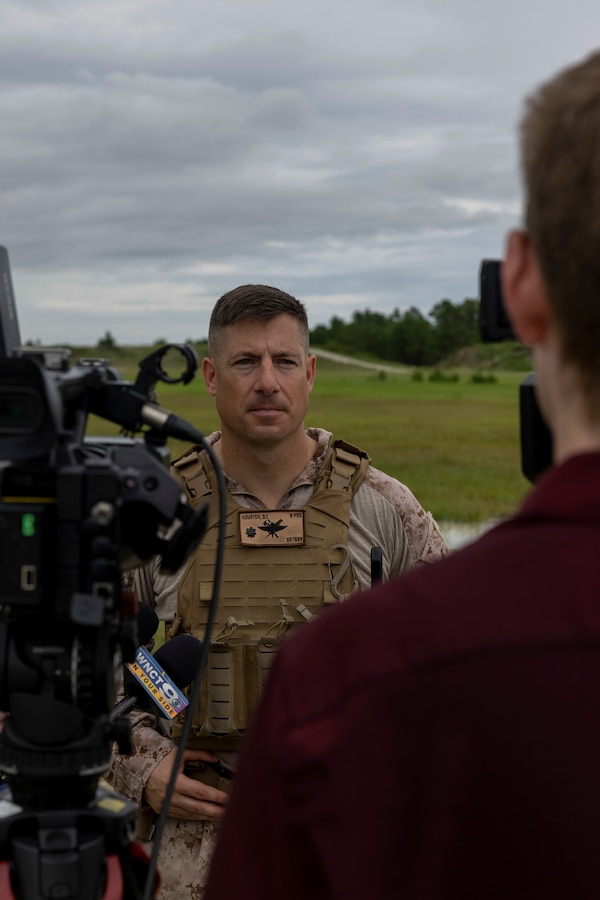 U.S. Marine Corps Lt. Col. Daniel T. Kovatch, center, commanding officer of 2nd Air Naval Gunfire Liaison Company, II Marine Expeditionary Force Information Group, is interviewed by media during exercise Burmese Chase 25 at Marine Corps Base Camp Lejeune, North Carolina, Aug. 12, 2025. Burmese Chase is an annual U.S. led, multi-lateral training exercise comprised of integrating ground and air fires, infantry tactics and naval gunfire alongside NATO allies to enhance combat readiness and interoperability. (U.S. Marine Corps photo by LCpl. Payton Walley)