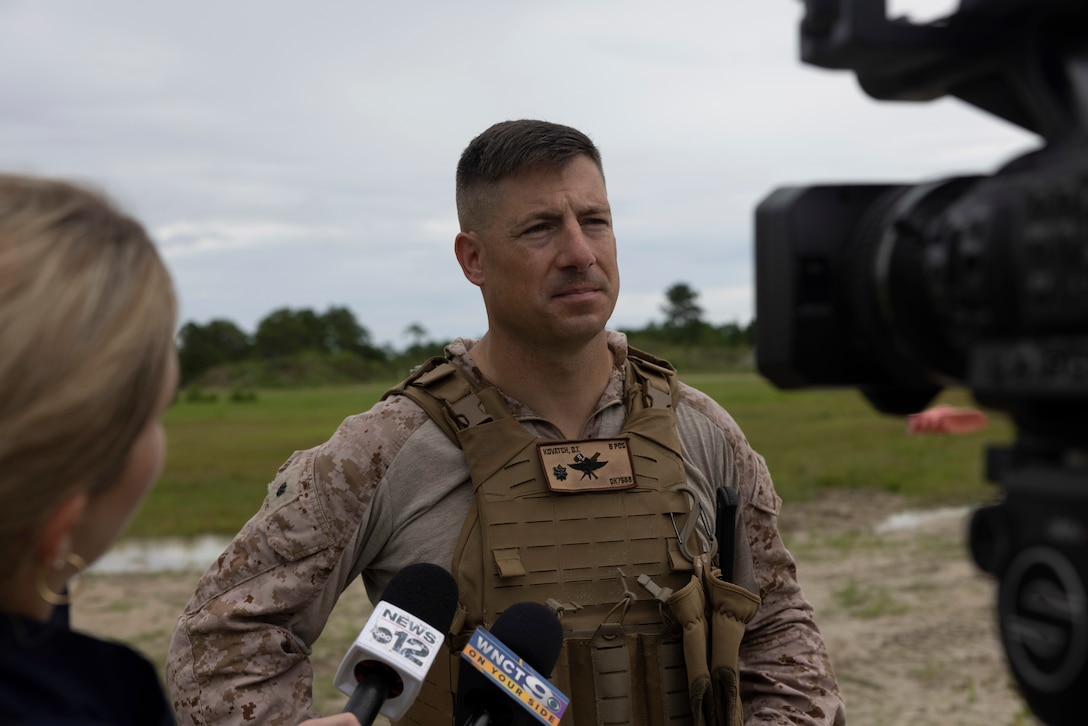 U.S. Marine Corps Lt. Col. Daniel T. Kovatch, center, commanding officer of 2nd Air Naval Gunfire Liaison Company, II Marine Expeditionary Force Information Group, is interviewed by media during exercise Burmese Chase 25 at Marine Corps Base Camp Lejeune, North Carolina, Aug. 12, 2025. Burmese Chase is an annual U.S. led, multi-lateral training exercise comprised of integrating ground and air fires, infantry tactics and naval gunfire alongside NATO allies to enhance combat readiness and interoperability. (U.S. Marine Corps photo by LCpl. Payton Walley)