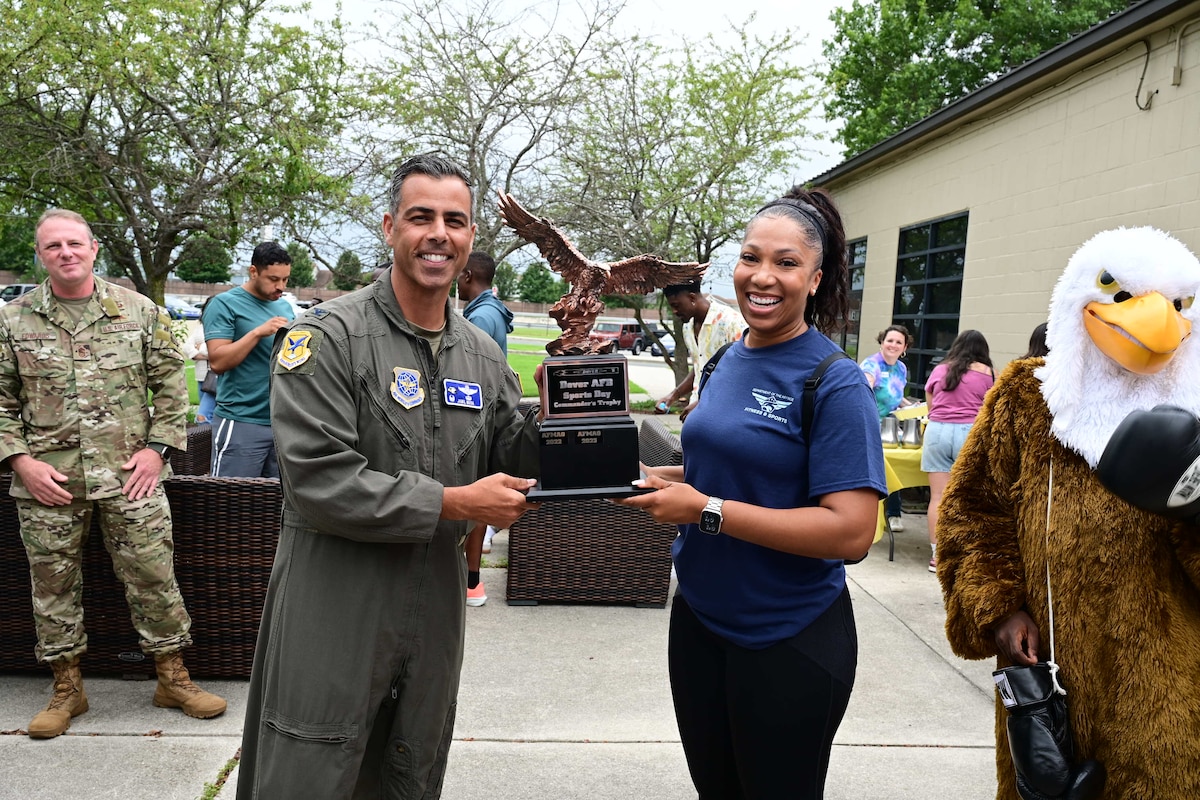U.S. Air Force Col. Jamil Musa, left, 436th Airlift Wing commander, hands the winner of the 2025 Commander’s Cup trophy to Lt.Col. DiAundra Walker, 436th Force Support Squadron commander, at the conclusion of the Wing Sports Day at Dover Air Force Base, Delaware, Aug. 1, 2025. Team Dover Airmen participated in various competitions which included a 5K run, soccer, tug of war, cornhole, powerlifting, 3-on-3 basketball and volleyball tournaments. The base-wide event fostered teamwork, camaraderie, resilience and physical conditioning. (U.S. Air Force photo by Mauricio Campino)