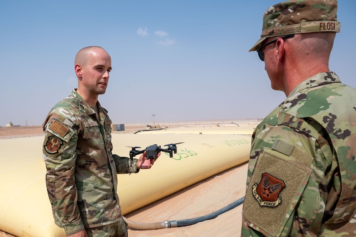 A man shows a drone to another man.