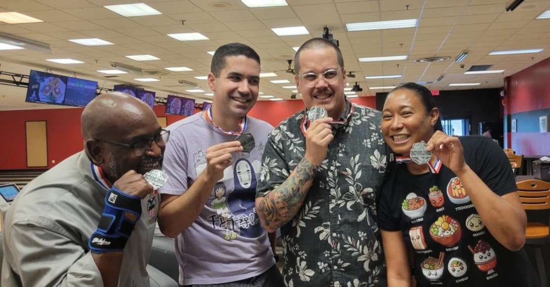 Three men and a lady hold silver medals