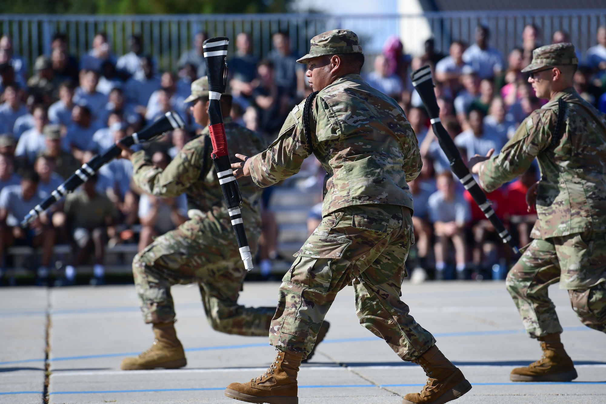 A group of men in military uniform spins static weapons in the air.