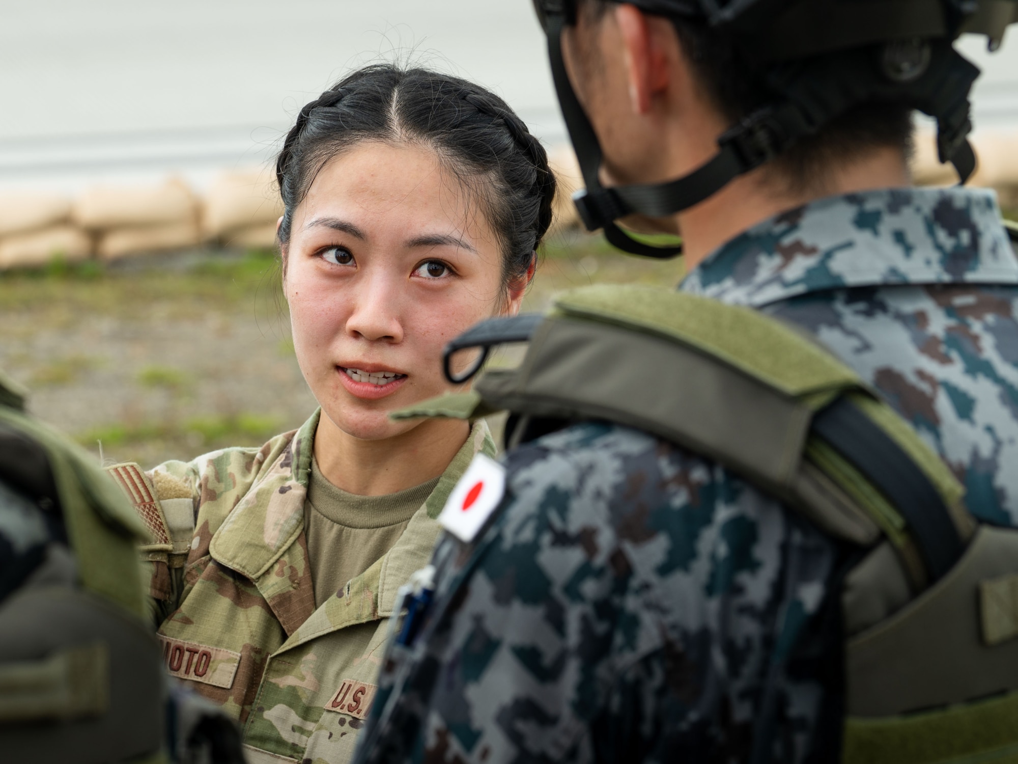 U.S. Air Force 2nd Lt. Julie Tatemoto, 51st Operations Support Squadron, airfield operations officer, speaks to a member of the Japan Air Self-Defense Force’s 2nd Contingency Response Team during the U.S. Air Force’s 2025 Department-Level Exercise series at Andersen Air Force Base, Guam, July 16, 2025. Tatemoto is supporting the DLE under the Language Enabled Airman Program, which deliberately develops language enabled, cross-cultural service members with working-level foreign language proficiency to better support the application of air and space power through strengthening partnerships, interoperability, and adversary understanding. The DLE series encompasses all branches of the Department of Defense, along with Allies and partners, employing more than 400 Joint and coalition aircraft and more than 12,000 members at more than 50 locations across 3,000 miles. (U.S. Air Force photo by Tech. Sgt. Joshua Smoot)