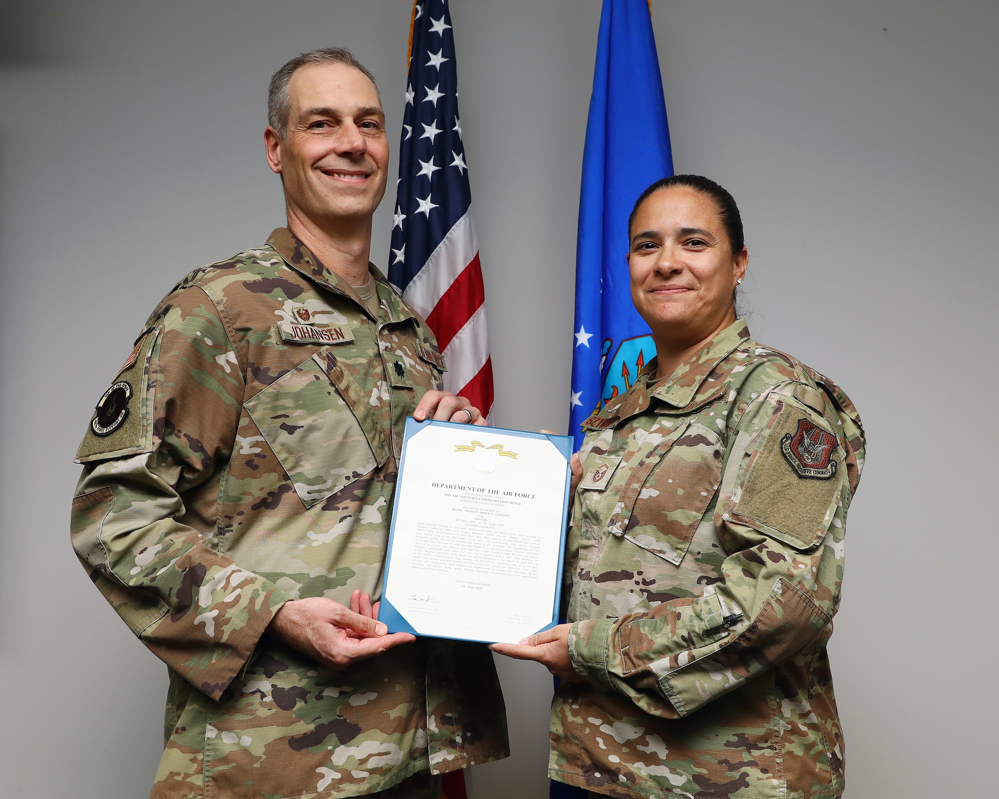 U.S. Air Force Lt. Col. Timothy Johansen, 445th Force Support Squadron commander, presents Master Sgt. Amanda Szymanski, 445th FSS personnel technician, with the Air and Space Commendation Medal at Wright-Patterson Air Force Base, Ohio, Aug. 3, 2025. Szymanski distinguished herself by providing first aid to an injured woman while on a camping trip July 26, 2025. (U.S. Air Force photo by Amanda Dick)