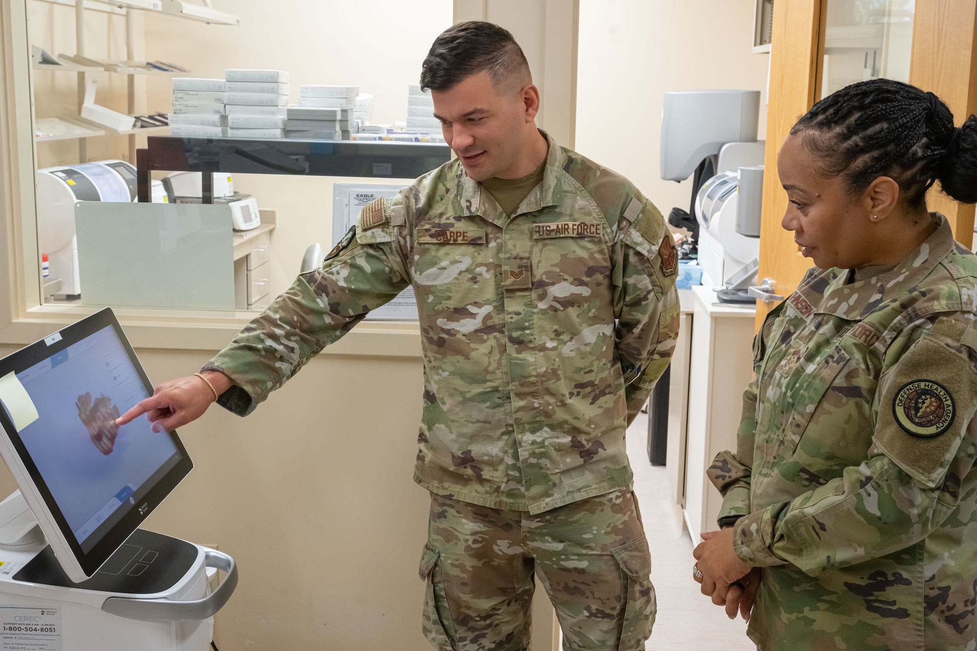 U.S. Air Force Chief Master Sgt. Tanya Johnson, Defense Health Agency senior enlisted leader, receives a dental lab briefing from U.S. Air Force Staff Sgt. Christopher Carpe, 5th Medical Group dental assistant on Minot Air Force Base, North Dakota on Aug.13, 2025.