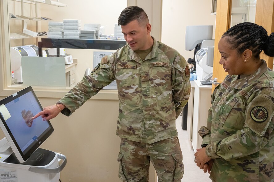 U.S. Air Force Chief Master Sgt. Tanya Johnson, Defense Health Agency senior enlisted leader, receives a dental lab briefing from U.S. Air Force Staff Sgt. Christopher Carpe, 5th Medical Group dental assistant on Minot Air Force Base, North Dakota on Aug.13, 2025.