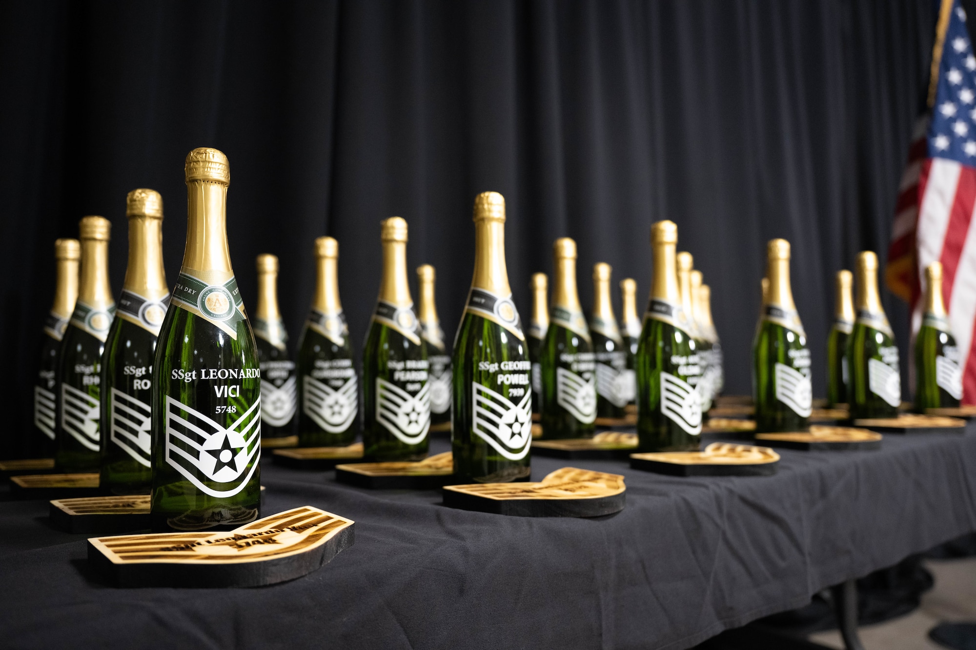 Custom made U.S. Air Force Staff Sgt. plaques and champagne bottles are prepared moments before a Staff Sgt. release social at XL Landings, Aug. 18, 2025. Team XL recognized 25 Senior Airmen for being selected for promotion to the rank of Staff Sgt. (U.S. Air Force photo by Airman 1st Class Darryl Keith.)