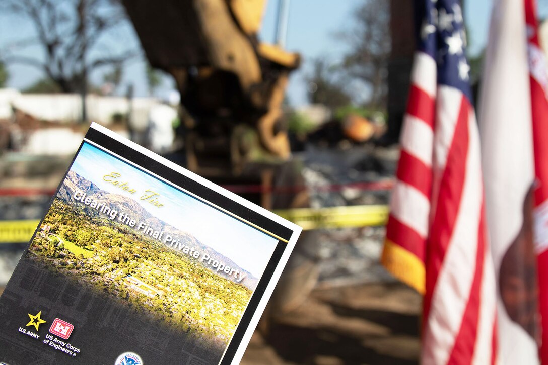 A program for an Aug. 14 ceremony is displayed in front of a property owned by Beverly and Tami Outterbridge Aug. 14 in Altadena, California. The ceremony was in honor of the debris removal at the Outterbridge's property, which is the last property assigned to the U.S. Army Corps of Engineers in the Eaton Fire's impacted area.