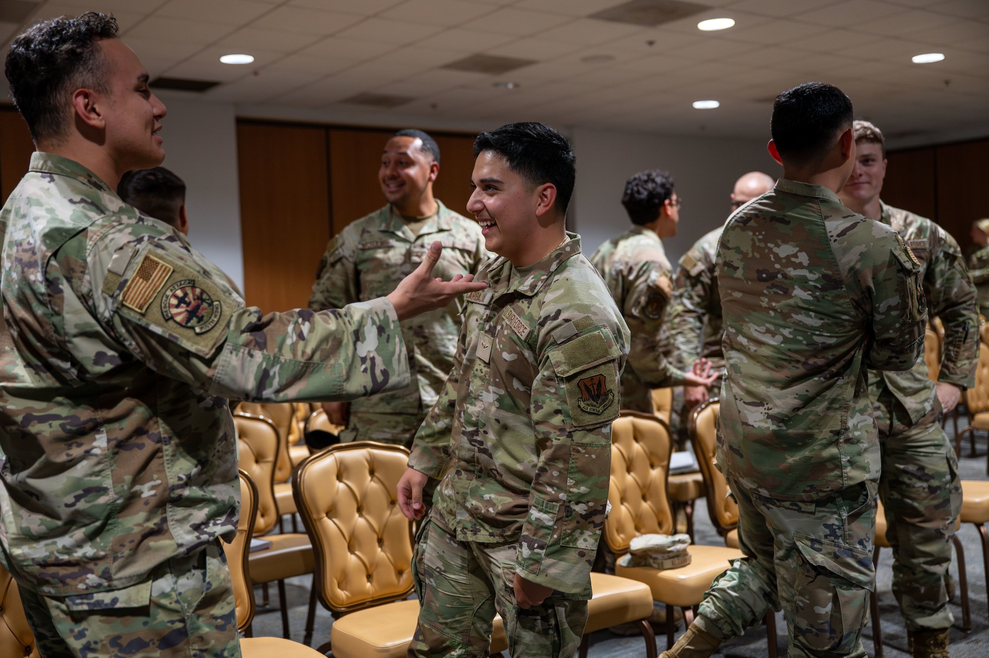 U.S. Airmen greet each other at the beginning of a speech led by retired Army Command Sgt. Maj. John Wayne Troxell, 3rd Senior Enlisted Advisor to the Chairman of the Joint Chiefs of Staff at Davis-Monthan Air Force Base, Arizona, Aug. 14, 2025. Troxell prompted Airmen to greet each other like an old friend to set a positive tone. (U.S. Air Force photo by Senior Airman Jasmyne Bridgers-Matos)
