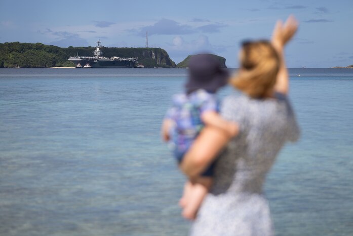 APRA HARBOR, Guam (Aug. 17, 2025) A Navy family watches as Nimitz-class aircraft carrier USS George Washington (CVN 73) arrives in Guam for a scheduled port visit, Aug. 17. George Washington is the U.S. Navy’s premier forward-deployed aircraft carrier, a long-standing symbol of the United States’ commitment to maintaining a free and open Indo-Pacific region, operating alongside allies and partners across the U.S. 7th Fleet area of responsibility. (U.S. Navy photo by Lt. Cmdr. Michelle Tucker)
