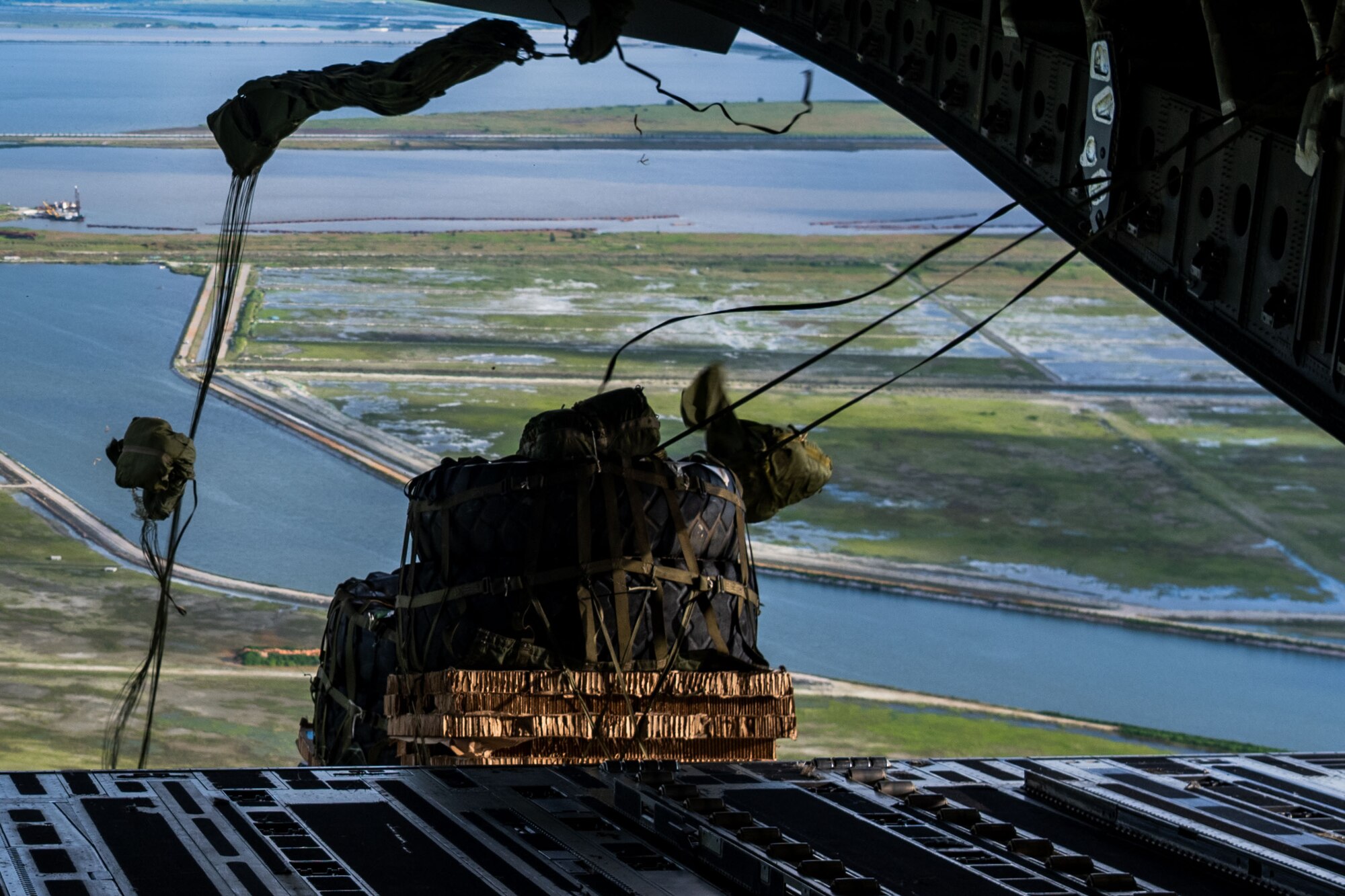 Cargo drops from a C-17 Globemaster III aircraft during a local training event over Kunsan Air Base, South Korea, July 21, 2025. Air Mobility Command aircraft enable local, routine training and operations to deliver rapid global mobility, ensuring U.S. and Allied forces can project power and respond swiftly anywhere in the world. With a fleet of versatile aircraft, AMC provides the critical capability to transport personnel, equipment, and supplies when and where needed. (U.S. Air Force photo by Senior Airman Zachary Foster)