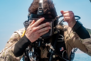An AFSOC Air Commando assigned dons their mask before conducting a SCUBA dive during Emerald Warrior 25.2.