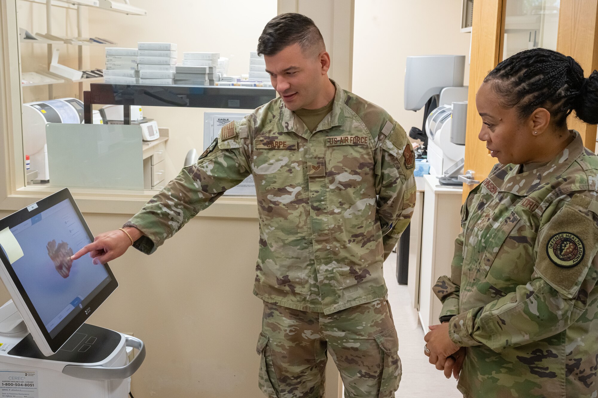 U.S. Air Force Chief Master Sgt. Tanya Johnson, Defense Health Agency senior enlisted leader, receives a dental lab briefing from U.S. Air Force Staff Sgt. Christopher Carpe, 5th Medical Group dental assistant on Minot Air Force Base, North Dakota on Aug.13, 2025.