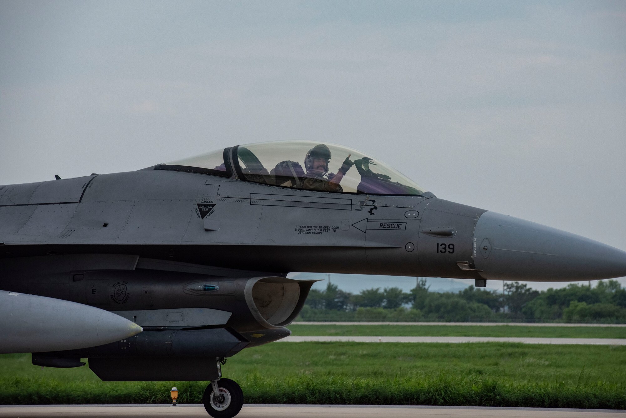 A U.S. Air Force F-16 Fighting Falcon pilot assigned to the 36th Fighter Squadron gives his squadron’s hand signal while taxiing during Ulchi Freedom Shield 25 at Osan Air Base, Republic of Korea, Aug. 18, 2025.