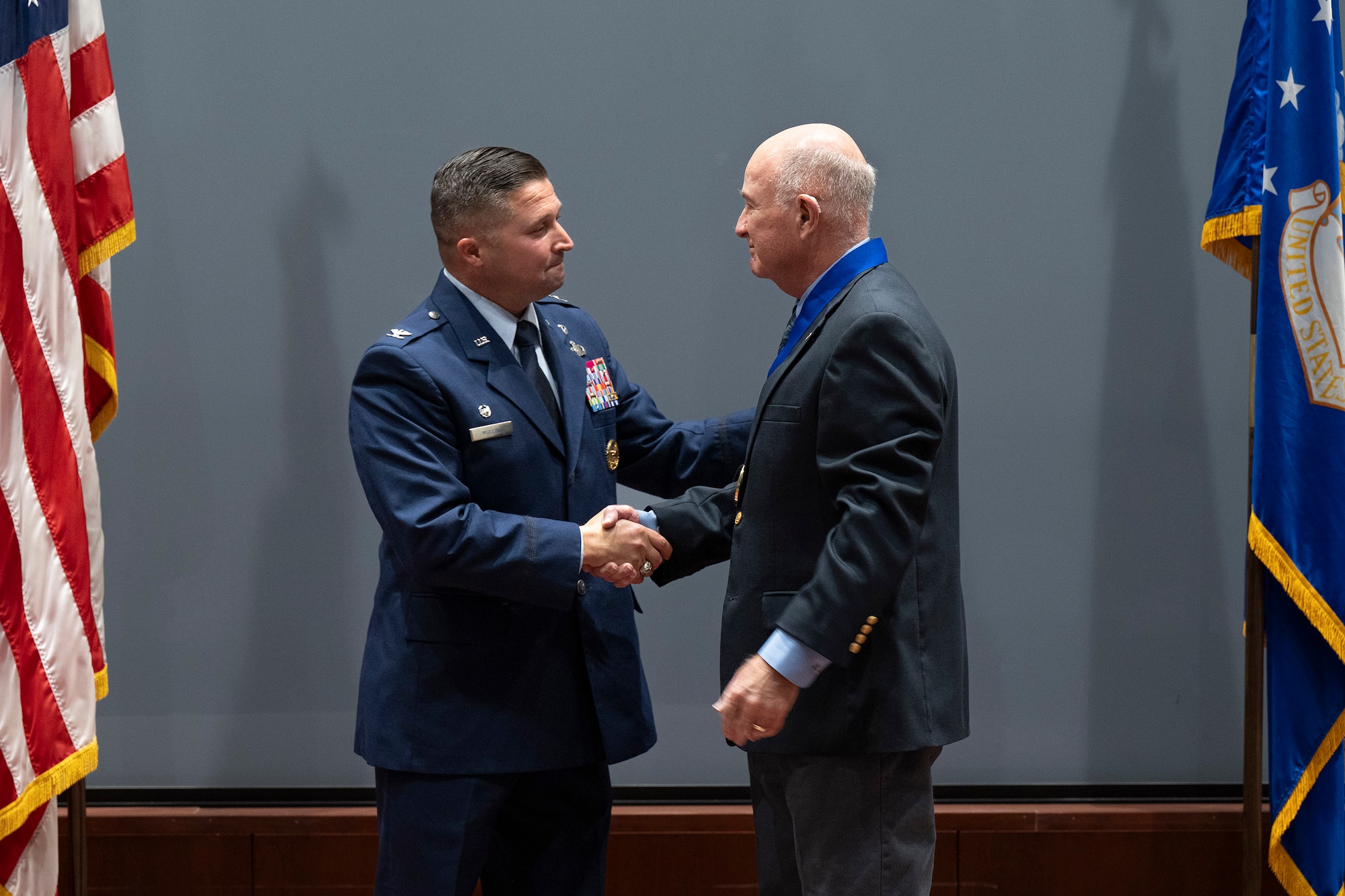 Col. Creighton Mullins, commander of the Air Force Technical Applications Center at Patrick Space Force Base, Fla., congratulates AFTAC’s 2025 Wall of Honor recipient, retired Air Force Maj. Louis W. Seiler Jr., during a ceremony held in the center’s Northrup Auditorium July 15, 2025.  “Lou Seiler is a living legend at AFTAC and in the field of nuclear surveillance,” said Mullins.  (U.S. Air Force photo by Matthew S. Jurgens)