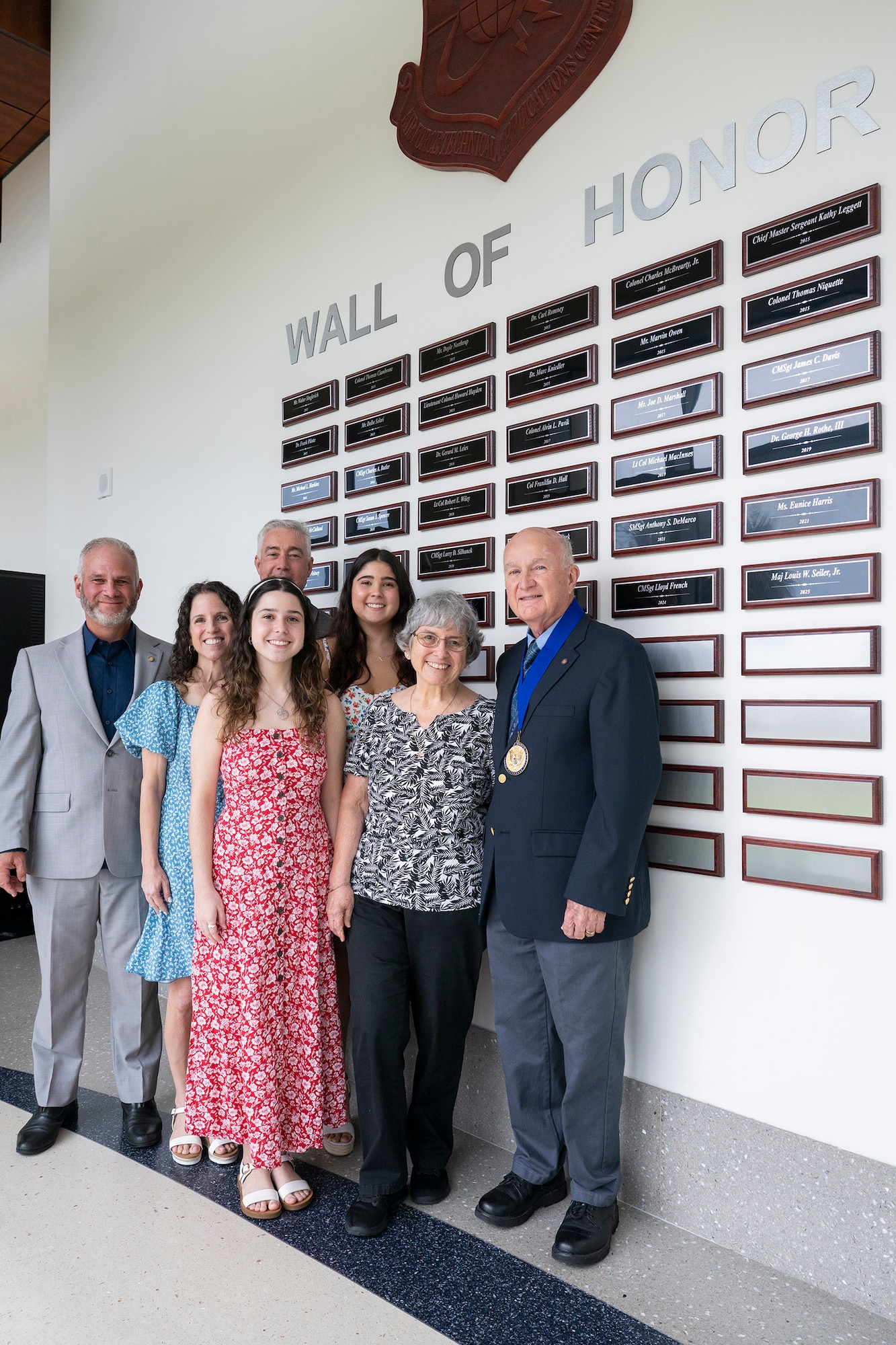 Retired Air Force Maj. Louis W. Seiler Jr. (right) stands with his family after his name was inscribed on the Air Force Technical Applications Center’s Wall of Honor at a ceremony July 15, 2025.  The wall recognizes past members who demonstrated great character and whose actions truly discriminated them from thousands of other center employees, both military and civilian. Pictured with Seiler are (from left to right): Kevin Seiler, son; Pamela Hughes, daughter; Amelia Hughes, granddaughter; Chris Hughes, son-in-law; Nicole Hughes, granddaughter, Joan Seiler, wife; and Lou Seiler, inductee. (U.S. Air Force photo by Matthew S. Jurgens)