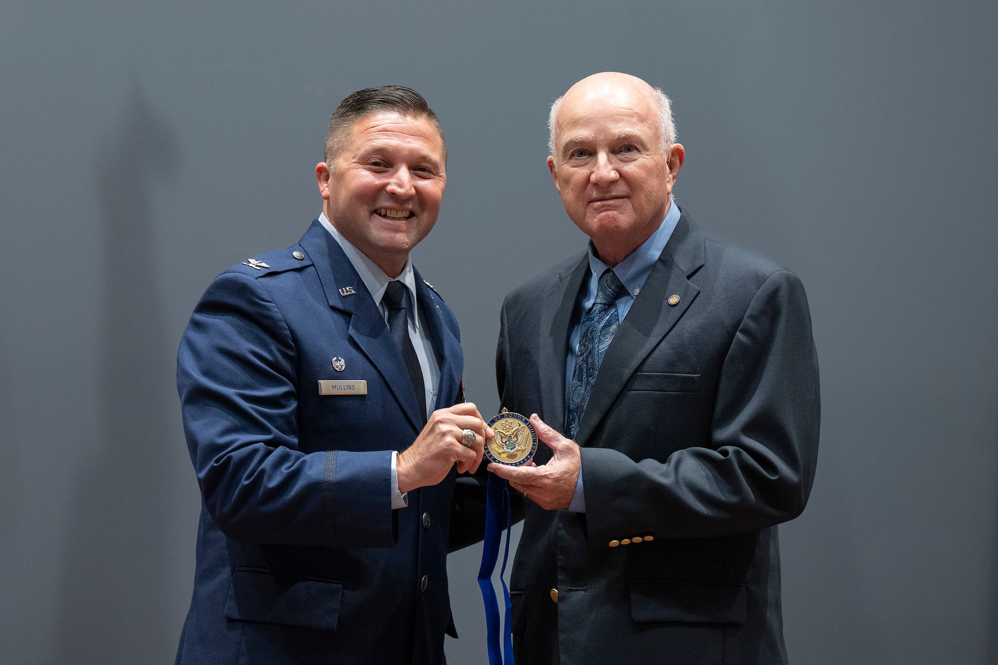 Col. Creighton Mullins, commander of the Air Force Technical Applications Center at Patrick Space Force Base, Fla., presents the Wall of Honor medallion to retired Air Force Maj. Louis W. Seiler Jr., during a ceremony honoring Seiler’s contributions to AFTAC’s long range detection mission. Seiler served 10 of his 20 years on active duty with the nuclear surveillance center.  (U.S. Air Force photo by Matthew S. Jurgens)